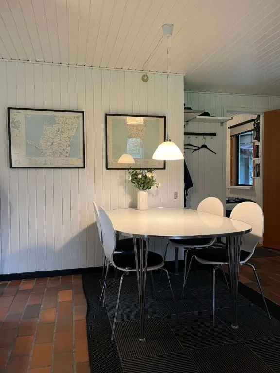 Lyst spisebord med stole i sommerhuset på Langeland, omgivet af hyggelig indretning og naturligt.